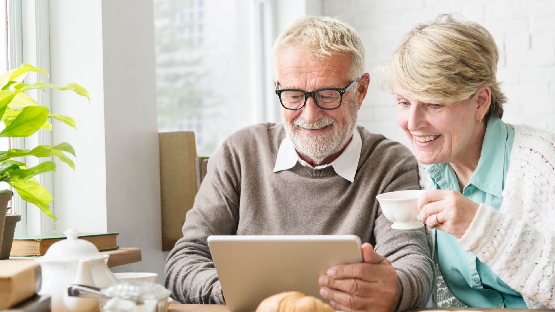 older couple looking happily at an ipad in their kitchen sorting out their estate planning